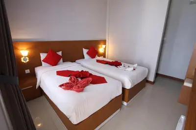 two beds in a hotel room with red bows on them at Tom Guest House in Legian