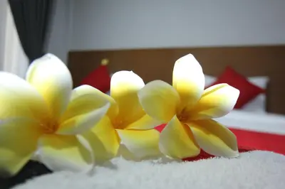 two yellow flowers sitting on top of a bed at Tom Guest House in Legian