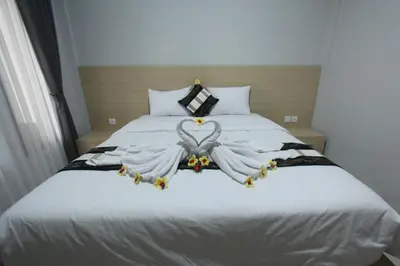 a bedroom with a bed with two white angel wings at Tom Guest House in Legian