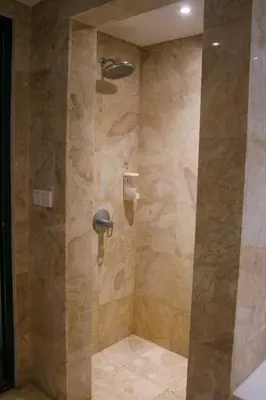 a bathroom with a shower with a stone wall at Dekuta in Kuta