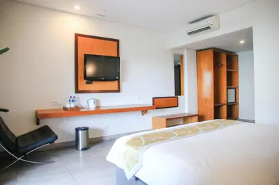 a bedroom with a bed and a tv on the wall at Dekuta in Kuta