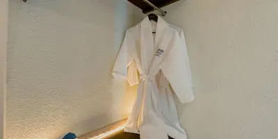 a white robe hanging on a wall at Aruni Bali Jimbaran Boutique Villa in Jimbaran