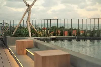 a swimming pool with benches on a building at Borough Capsule Hostel Bali in Legian