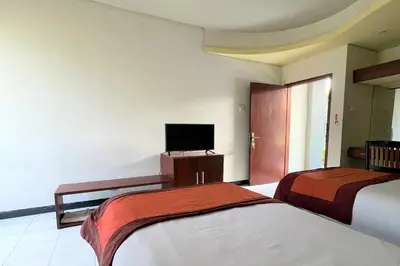 a hotel room with two beds and a flat screen tv at The Yani Hotel Bali in Denpasar