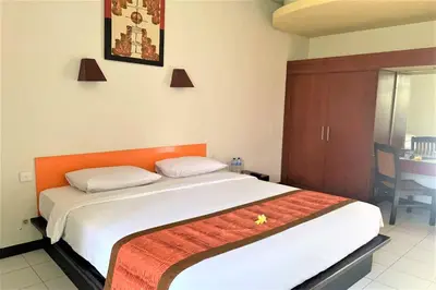 a bedroom with a large bed with an orange headboard at The Yani Hotel Bali in Denpasar