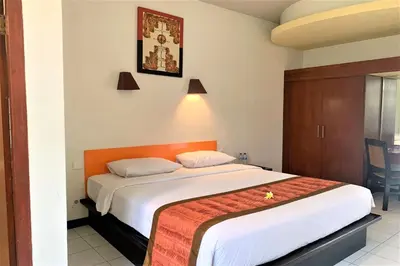 a bedroom with a large bed with an orange headboard at The Yani Hotel Bali in Denpasar