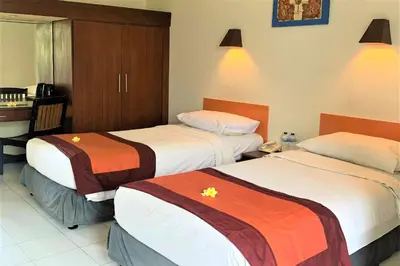 a hotel room with two beds and a desk at The Yani Hotel Bali in Denpasar