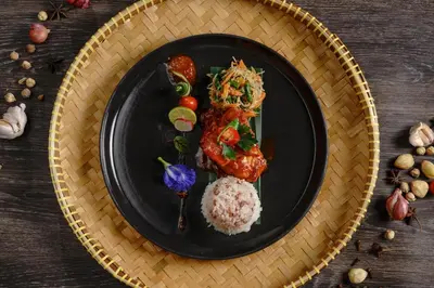 a black plate of food with rice and vegetables at Kayumanis Jimbaran Private Villas & Spa in Jimbaran