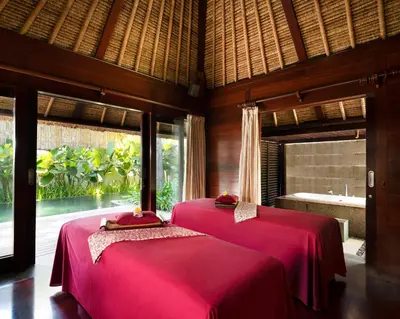 two beds in a room with a bathroom with a tub at Kayumanis Jimbaran Private Villas & Spa in Jimbaran