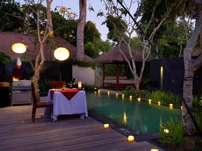 a backyard with a table and a swimming pool at night at Kayumanis Jimbaran Private Villas & Spa in Jimbaran