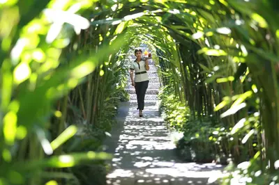 a woman walking down a path through a bamboo tunnel at Ziva a Boutique Villa in Seminyak