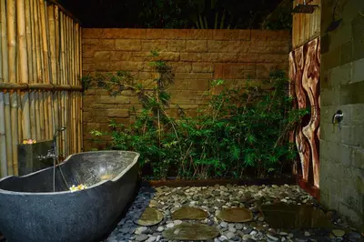 a bath tub sitting on top of a stone floor at The Garden Villa in Sanur