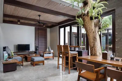 a living room with a table and a tree at Le Jardin Villas Seminyak in Seminyak