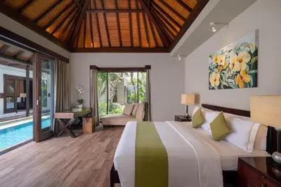 a bedroom in a villa with a bed and a pool at Le Jardin Villas Seminyak in Seminyak