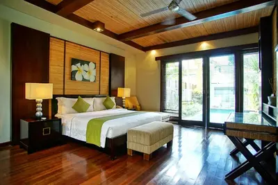 a bedroom with a large bed and a large window at Le Jardin Villas Seminyak in Seminyak