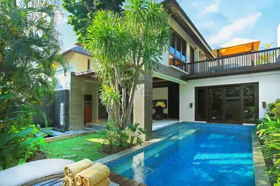 a villa with a swimming pool in front of a house at Le Jardin Villas Seminyak in Seminyak