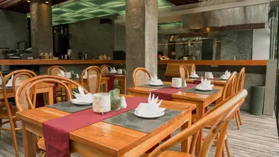 a restaurant with wooden tables and chairs with napkins on them at Annora Villas Seminyak in Seminyak