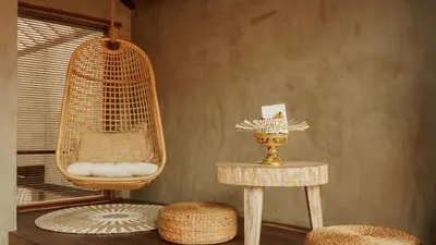 a room with a rattan chair and a table and stool at Annora Villas Seminyak in Seminyak