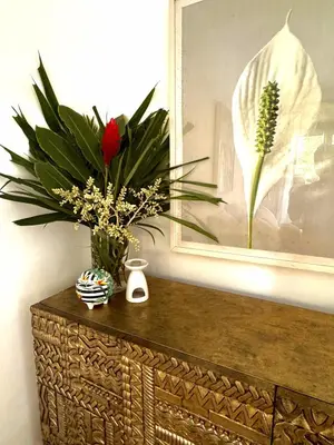 a wooden cabinet with a vase of flowers on top of it at Baby Melon Villas in Seminyak