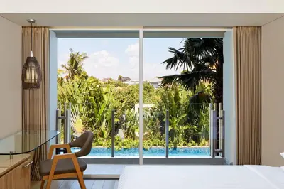 a bedroom with a view of a pool through a window at Fairfield by Marriott Bali Legian in Legian