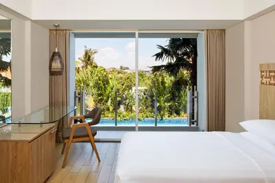a bedroom with a bed and a glass desk and a window at Fairfield by Marriott Bali Legian in Legian