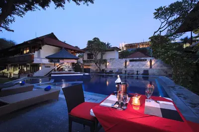 a table with a red table cloth next to a swimming pool at The Taman Ayu Seminyak 10 Minute walking to the BEACH in Seminyak