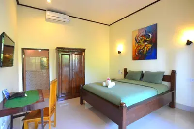 a bedroom with a bed and a table and a desk at Arik Homestay Canggu in Canggu
