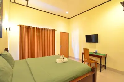 a bedroom with a bed and a desk and a television at Arik Homestay Canggu in Canggu