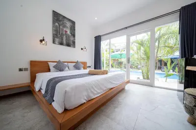 a bedroom with a large bed and a large window at Easy Surf Camp in Kuta