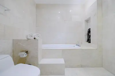 a white bathroom with a tub and a toilet at djabu Seminyak Hotel in Seminyak
