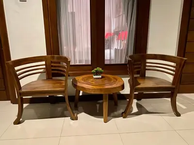 two wooden chairs and a table with a plant on it at Dikubu Belong Seminyak in Seminyak