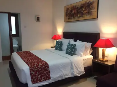a bedroom with a large bed with two lamps at Dikubu Belong Seminyak in Seminyak