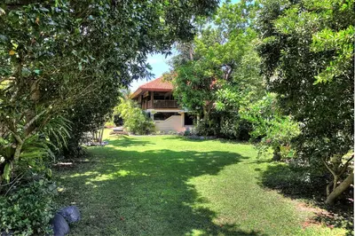 a house in the middle of a green yard with trees at Raja Gardens Hotel in Seminyak