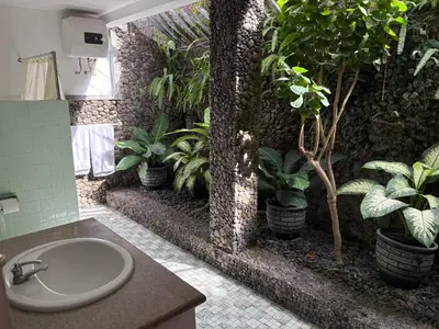 a bathroom with potted plants on a wall at Raja Gardens Hotel in Seminyak