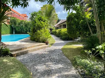 a garden with a swimming pool next to a house at Raja Gardens Hotel in Seminyak