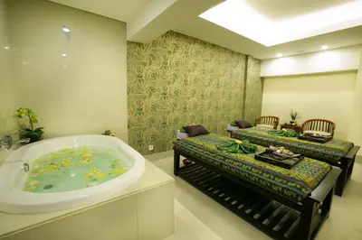 a bathroom with a tub and a couch and chairs at Legian Paradiso Hotel in Legian