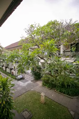 a courtyard with trees and benches in front of a building at Legian Paradiso Hotel in Legian