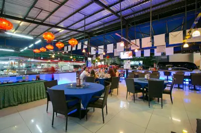 a restaurant with tables and chairs with people sitting at them at Legian Paradiso Hotel in Legian