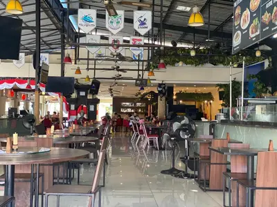 a restaurant with tables and chairs and people in it at Legian Paradiso Hotel in Legian