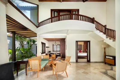 an open living room with a staircase and a table and chairs at The Club Villas Seminyak in Seminyak
