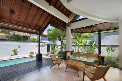 an outdoor living room with a pool and a table and chairs at The Club Villas Seminyak in Seminyak