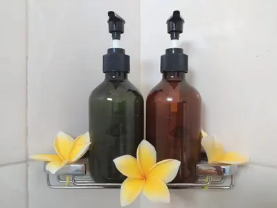two bottles on a rack with flowers on the wall at Kubu Green in Nusa Dua