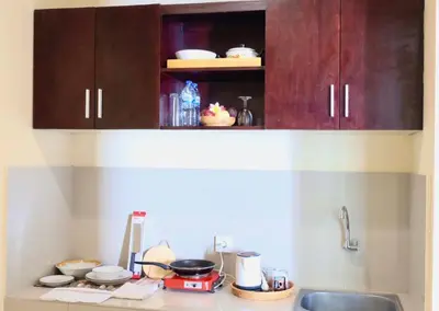 a kitchen counter with wooden cabinets and a sink at Kubu Green in Nusa Dua