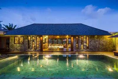 a villa with a swimming pool at night at Rachline Villa in Kerobokan