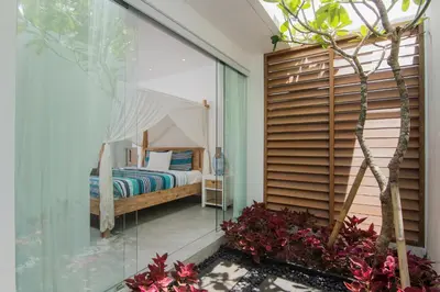 a bedroom with a bed in a glass wall at Villa Kobe Beachside Berawa Canggu location in Canggu