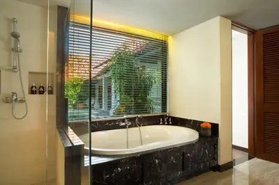 a bath tub in a bathroom with a window at Alaya Dedaun Kuta in Legian