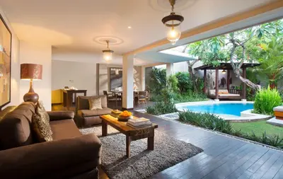 a living room with a couch and a table and a pool at Alaya Dedaun Kuta in Legian