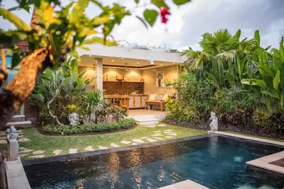 a house with a swimming pool in front of a yard at Kubu Kayu Villas in Seminyak