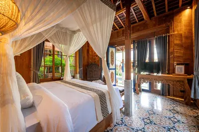 a bedroom with a large bed with white canopy at Kubu Kayu Villas in Seminyak