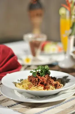 a plate of pasta with meat on a table at Jay's Villa Umalas in Canggu
